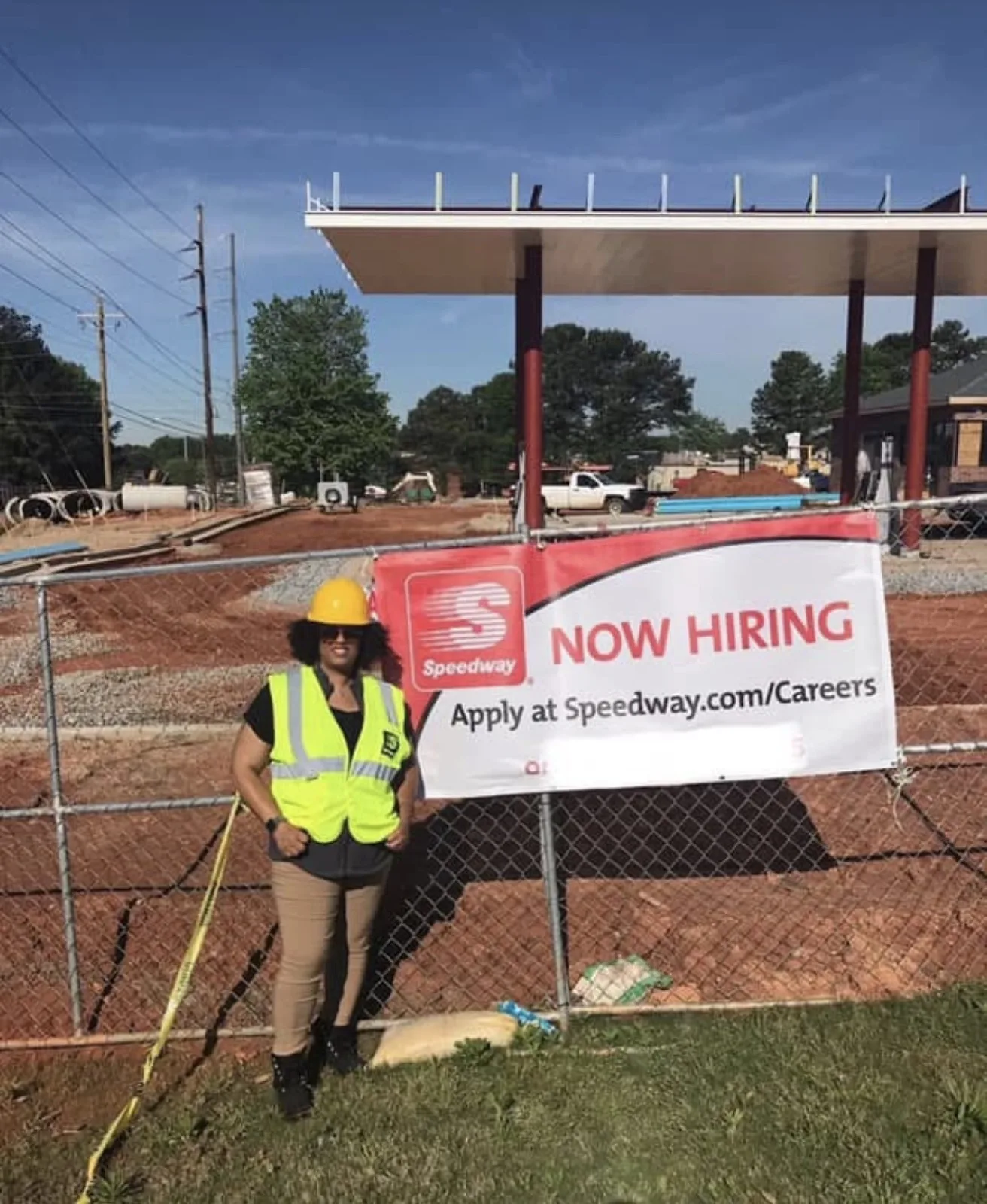 Java Hardge in a hard hat and safety vest at a Speedway construction site, standing beside a Now Hiring banner